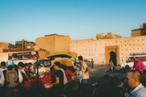 People selling goods in a bustling marketplace with buildings.