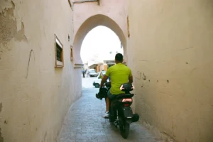A man riding a scooter down a narrow alley way