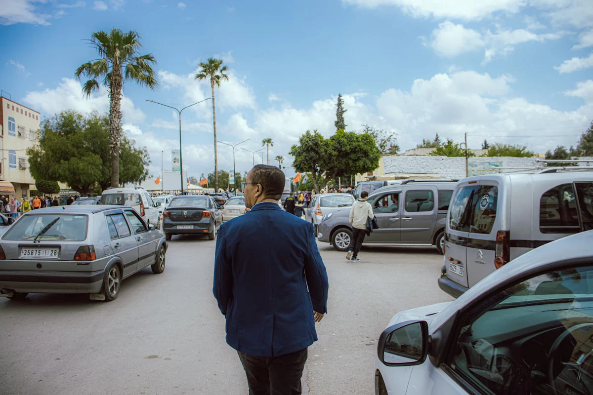 a man in a blue suit walking through a parking lot