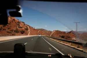 Un coche conduciendo por una carretera junto a una montaña