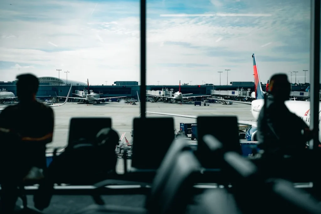 People waiting at an airport gate with planes outside
