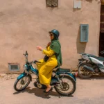 Woman rides a scooter in the sunny street.