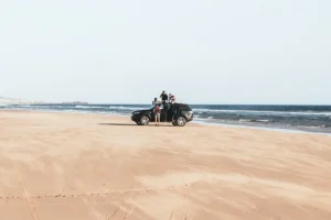 black vehicle parked on shore with four men during daytime