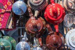 High-angle vibrant shot of traditional hand-painted metal and ceramic teapots with colorful geometric patterns on display at a local market.