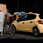 yellow volkswagen beetle parked beside man in white and blue plaid shirt