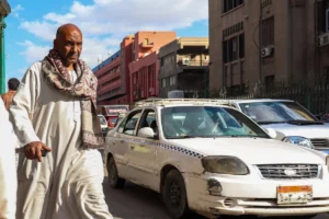 a man walking down a street next to a taxi