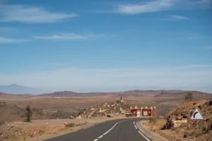 Winding road through arid desert landscape with red building.