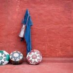 A group of three balls sitting next to a red wall