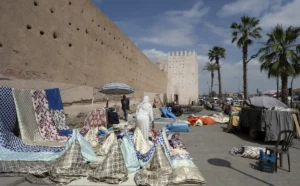 A market displays textiles in front of ancient walls