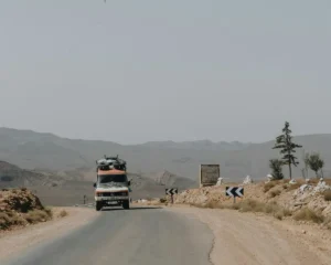 Truck driving on a dusty desert road with mountains